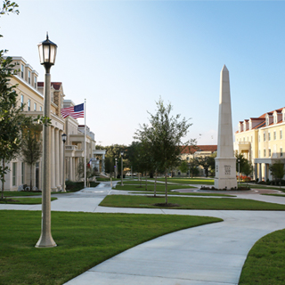Exterior of the Greek Village at TCU, where a tall obelisk monument bearing greek letters is surrounded group of sorority and fraternity houses Exterior of the Greek Village at TCU, where a tall obelisk monument bearing greek letters is surrounded group of sorority and fraternity houses