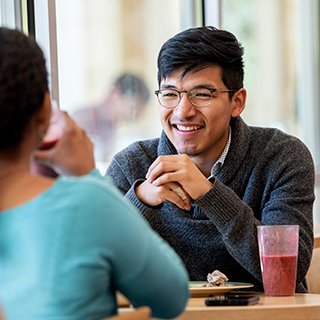 A young male student wearing glasses smiles across a table at a young woman in Market Square, the main TCU dining hall. A young male student wearing glasses smiles across a table at a young woman in Market Square, the main TCU dining hall.