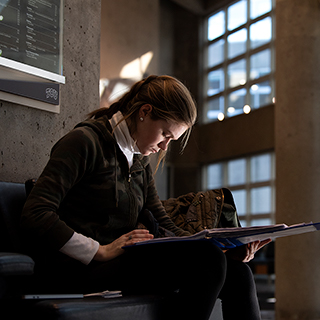 A young women sits alone and looks down intently at her book in the sunlit lobby of TCU's Moudy Hall North. A young women sits alone and looks down intently at her book in the sunlit lobby of TCU's Moudy Hall North.