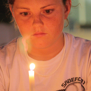 Close up of female TCU student looking thoughtful as she holds a candle before her face. Close up of female TCU student looking thoughtful as she holds a candle before her face.