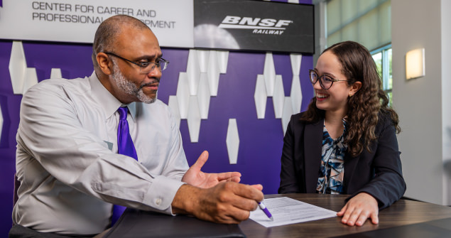 Career center professional with pen and paper interviewing a student