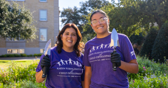 Two females wearing Karyn Purvis Institute of Child Development shirts show their gardening spades