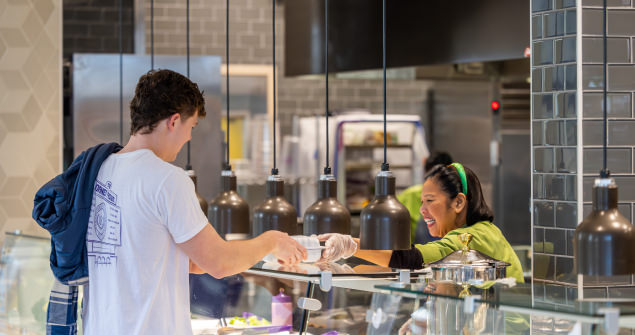 A student receives a carryout box from a TCU Dining staff member